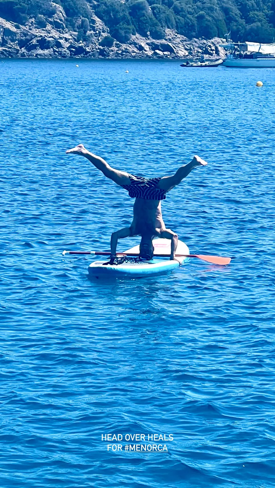 A handstand on a paddleboard in blue water
