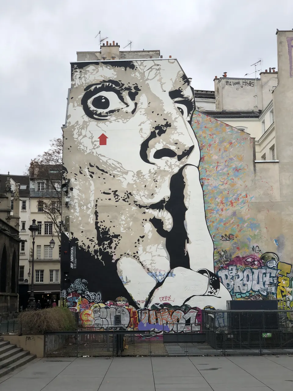 Mural of a face with a finger to its lips on an apartment building