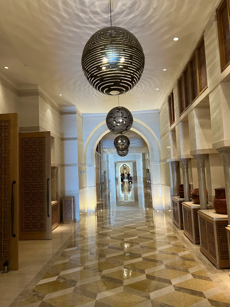 A hotel corridor under mirrored pendant lamps