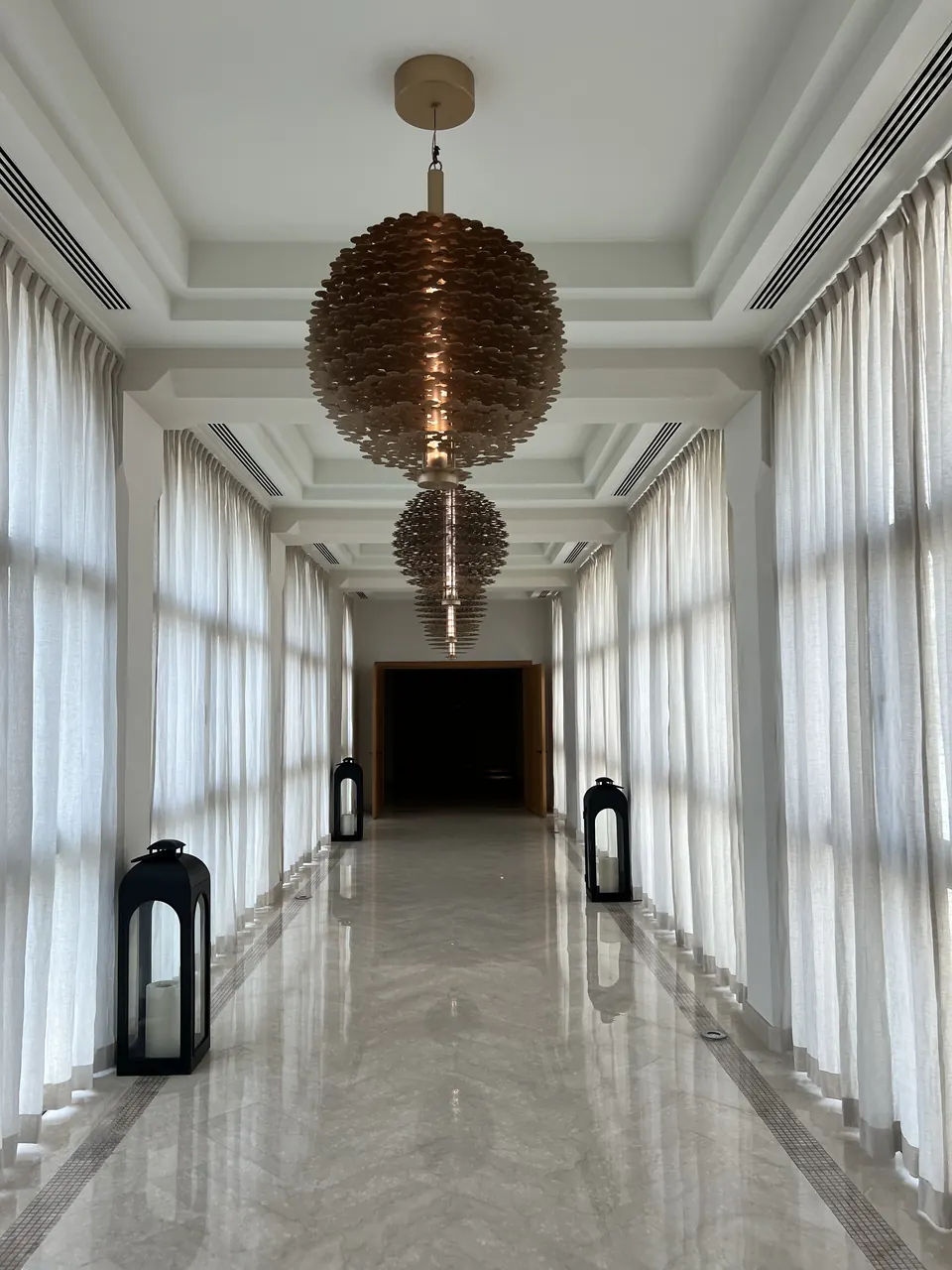 A white corridor under brass pendant lamps
