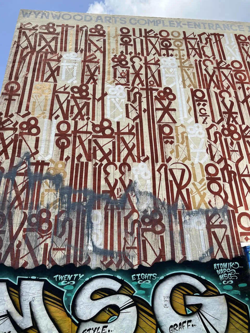 A wall of red and white glyphs above graffiti letters